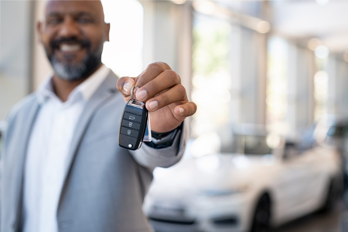 mandataire, avec en main la clé d'une voiture achetée par un client